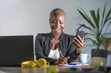 successful black afro American business woman working at modern office with mobile phone writing notes on notepad