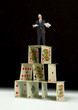 © Michael O'Keene - Man in business suit holding work folders with stressed out distraught look on his face standing on house of cards representing difficulties, work stress, uncertain stock market, housing bubble, etc.