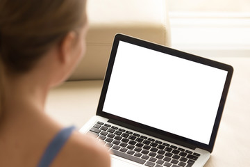 Casual woman looking at laptop with mockup blank screen. Empty copy space on monitor for  advertisement, language learning ad, online shopping website, social media site. Close up, focus on screen.