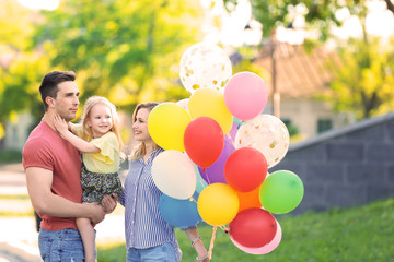 Wall Mural - Happy family with colorful balloons in park on sunny day