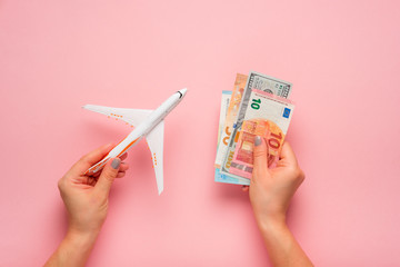 Wall Mural - Plane and money in hand on a pink background.  Travel concept.