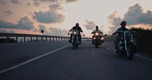 Young Male Bikers Riding Motorcycles On Highway At Sunset