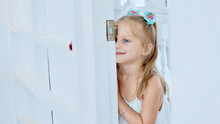 Little Cute Child Girl Peeks Through The Doorway In Room With Funny Emotions