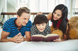 © Nattakorn - Mother, father and son, cute boy reading book, teaching homework on white bed, happy family and lifestyle concept