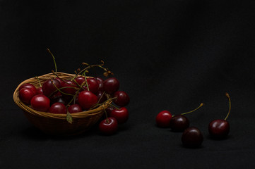 Wall Mural - Cherry in a wicker basket on a black background