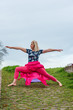 Attractive mature woman doing yoga outdoor in park, enjoying nature and fresh air. Longevity concept. Warrior II pose