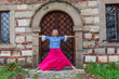 Attractive blond mature woman doing yoga poses outdoor,  in front of old fortress. Longevity concept 
