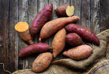 Mix Of Sweet Potatoes With Sack Over Wooden Background