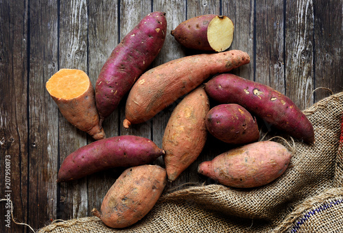 Fotomural Mix of sweet potatoes with sack over wooden background