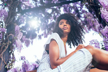 Young Black Woman Sitting Surrounded By Flowers