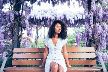 Young black woman sitting surrounded by flowers