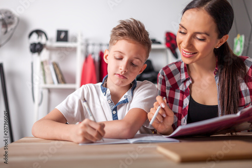 Mother Helping Her Son With Homework In Teenage Room At Home