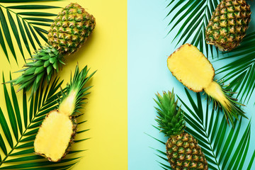  Pineapples, palm leaves on pastel colorful yellow and turquoise background with copy space. Creative summer concept. Flat lat, top view