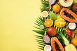 Exotic fruits and tropical palm leaves on pastel yellow background - papaya, mango, pineapple, banana, carambola, dragon fruit, kiwi, lemon, orange, melon, coconut, lime. Top view.