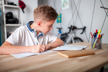 focused preteen boy doing homework on desk in his room
