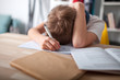 © leszekglasner - Bored and tired teenage boy doing homework on desk in his room