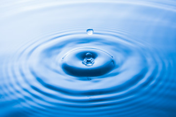  Water drop falling into water make waves. Water splash or water drop background.