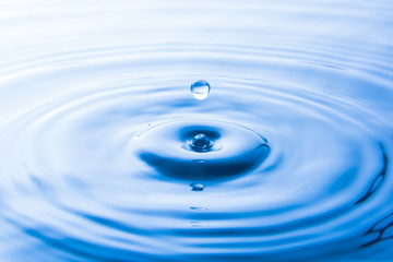  Krople wody wpadające do wody tworzą fale. Wodny pluśnięcia lub wody opadowy tło.