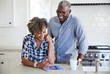 © Trinette Reed/Stocksy - African American Senior Couple looking at cell phone in the kitchen together
