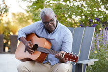 Closeup Portrait Of African American Senior Man Playing Guitar Outside