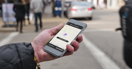 A woman holds a smartphone with a ride sharing app displaying her driver has arrived. Fictional interface, generic smartphone.