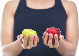 A woman in a fitness suit is holding an apple green and red.Healthy Eating Concept.Focus on apple.