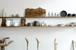 © Nicole Mason/Stocksy - wood shelves of ceramics, scissors and cutting boards on white wall of curated shop