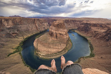 A Mans Legs Hanging Over The Edge Of Horse Shoe Bend