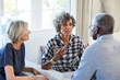 © Trinette Reed/Stocksy - Group of multiethnic senior friends visiting and talking in the living room at home