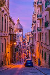 Wall Mural - Sunset view a narrow street with the carmelite church Our Lady of Mount Carmel in Valletta, Malta