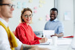 © pressmaster - Adult men in red shirt and multiracial colleagues writing on documents and having business meeting