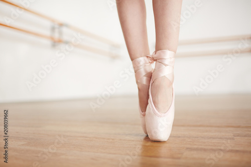 Fotografiet  Faceless ballerina doing exercises in pointe champagne color in light studio