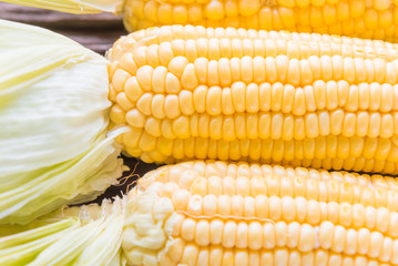 Fresh corn on cobs on rustic wooden table, closeup