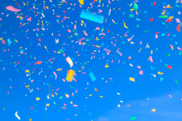 multicolored confetti on blue sky background