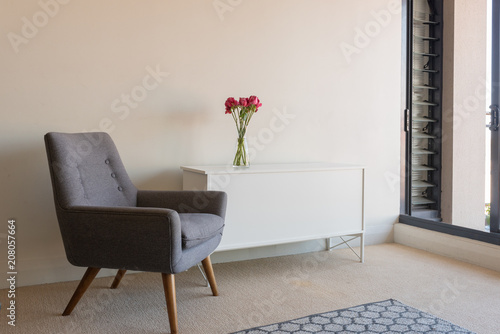 Fotografia, Obraz View of living room with retro grey armchair and white sideboard with red roses
