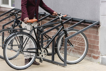 Wall Mural - cropped view of stylish man with bike on parking for bicycles