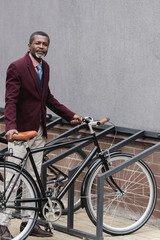 Wall Mural - fashionable mature african american businessman with bike on parking for bicycles