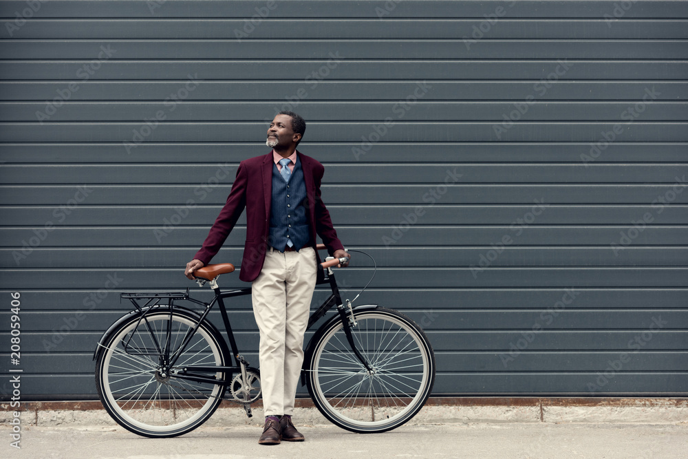 fashionable african american man in trendy jacket posing near bicycle - obrazy, fototapety, plakaty 