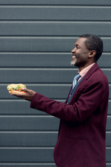 Wall Mural - fashionable smiling african american man holding burger