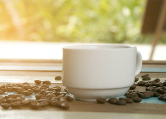 cup of coffee and beans with blurred green leaf background