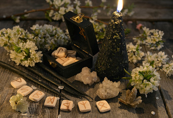 Wall Mural - Black candles with old runes, crystals and flowers on planks. Occult, esoteric and divination still life. Halloween background with vintage objects 