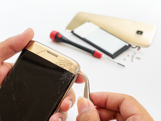 Wall Mural - Close-up of technician hand taking off cracked smartphone screen for preparing to repair or replace new screen on blurred smartphone component background