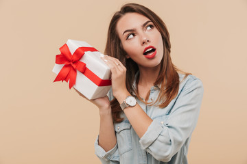 Canvas Print - Portrait of a wondering young girl holding present box