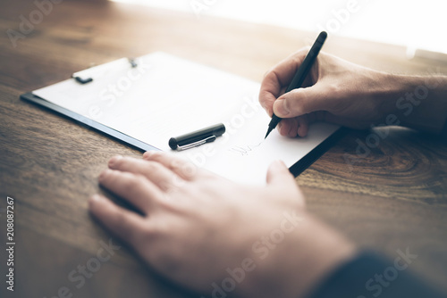 Fotomural close-up shot of businessman signing contract or document on wooden desk