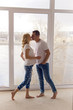 © saulich84 - pregnant girl standing with her husband next to the window