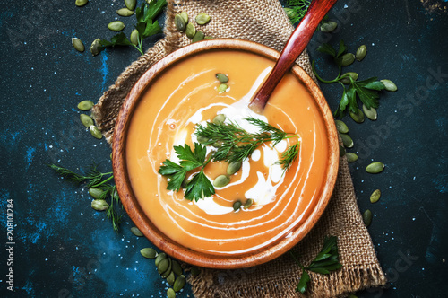 Fotografía Creamy pumpkin soup with herbs and seeds in wooden bowl, rustic style, black bac