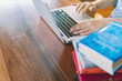 © aksonsat - Close-up photo of hand businesswoman typing on keyboard and book stack on Wooden table desk in office work place room. Copy space concetp.