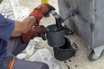 Wall Mural - Worker filling a tar bucket from boiler for melting pitch