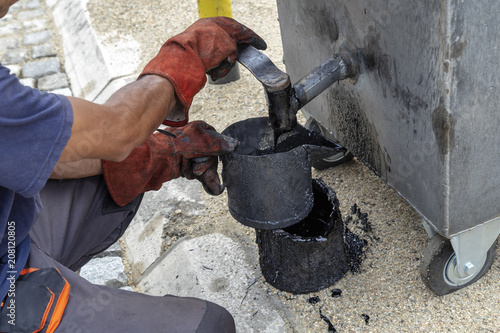 Worker filling a tar bucket from boiler for melting pitch - Buy ...