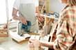 © pressmaster - Two faceless woman standing near workbench in carpenter workshop and working with wood.